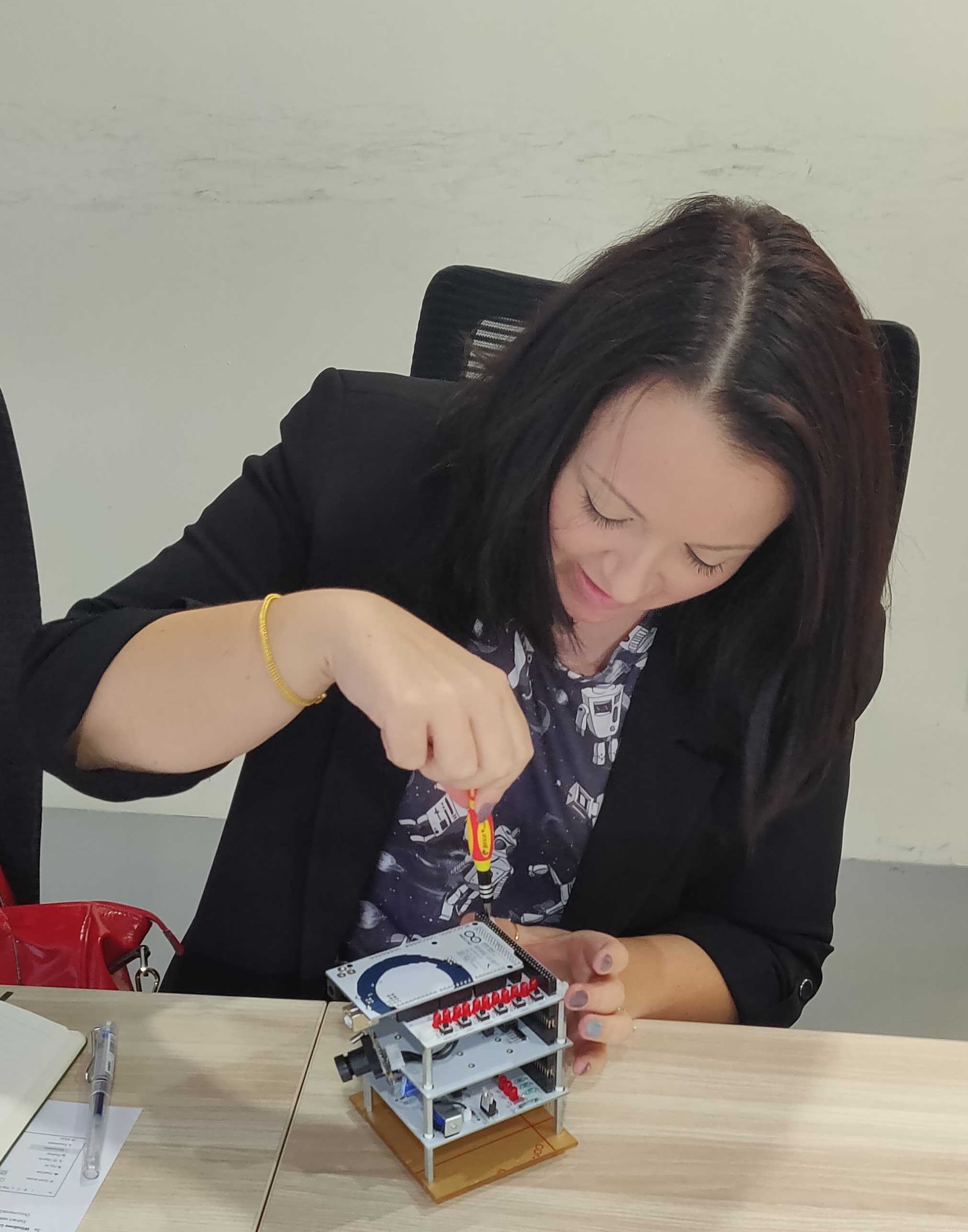 Alex working on a nanosatellite in a Singapore lab, November 2019, holding a screwdriver to a circuit board frame.